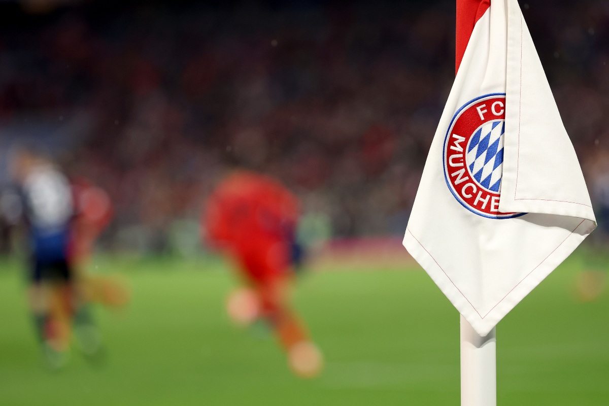 A corner flag displays the Bayern Munich crest inside the Allianz Arena.