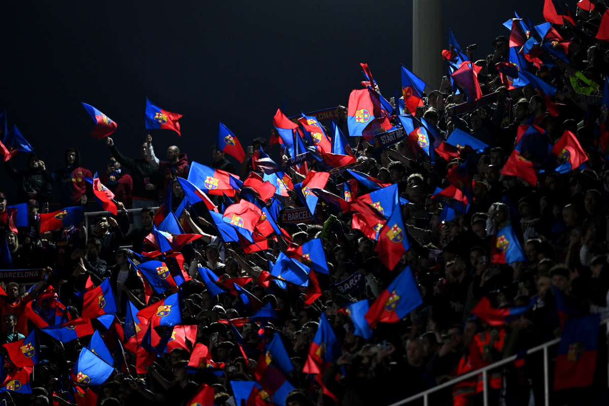 Barcelona fans wave flags with the club logo on.