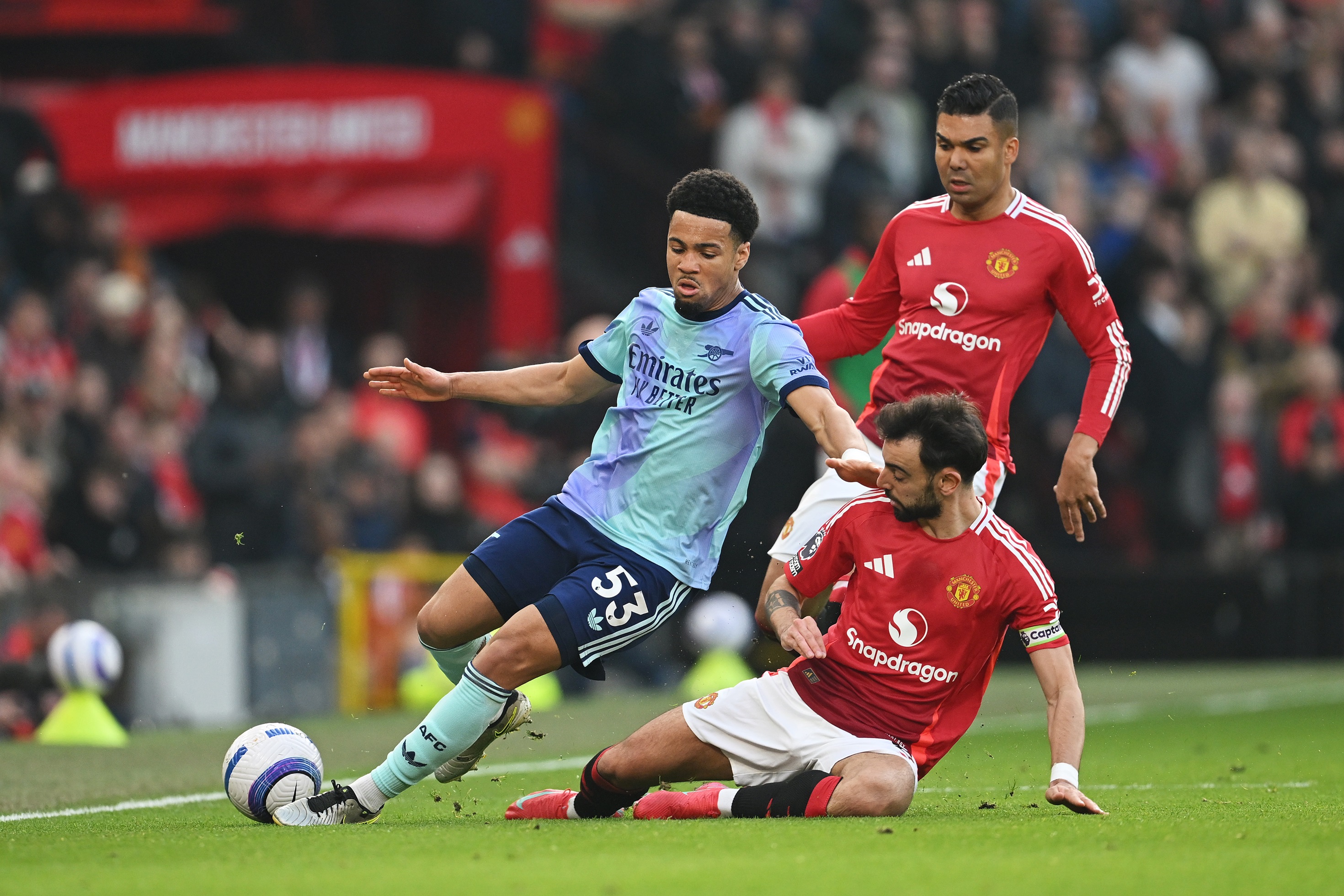 Casemiro watches on as Bruno Fernandes slide tackles Ethan Nwaneri.