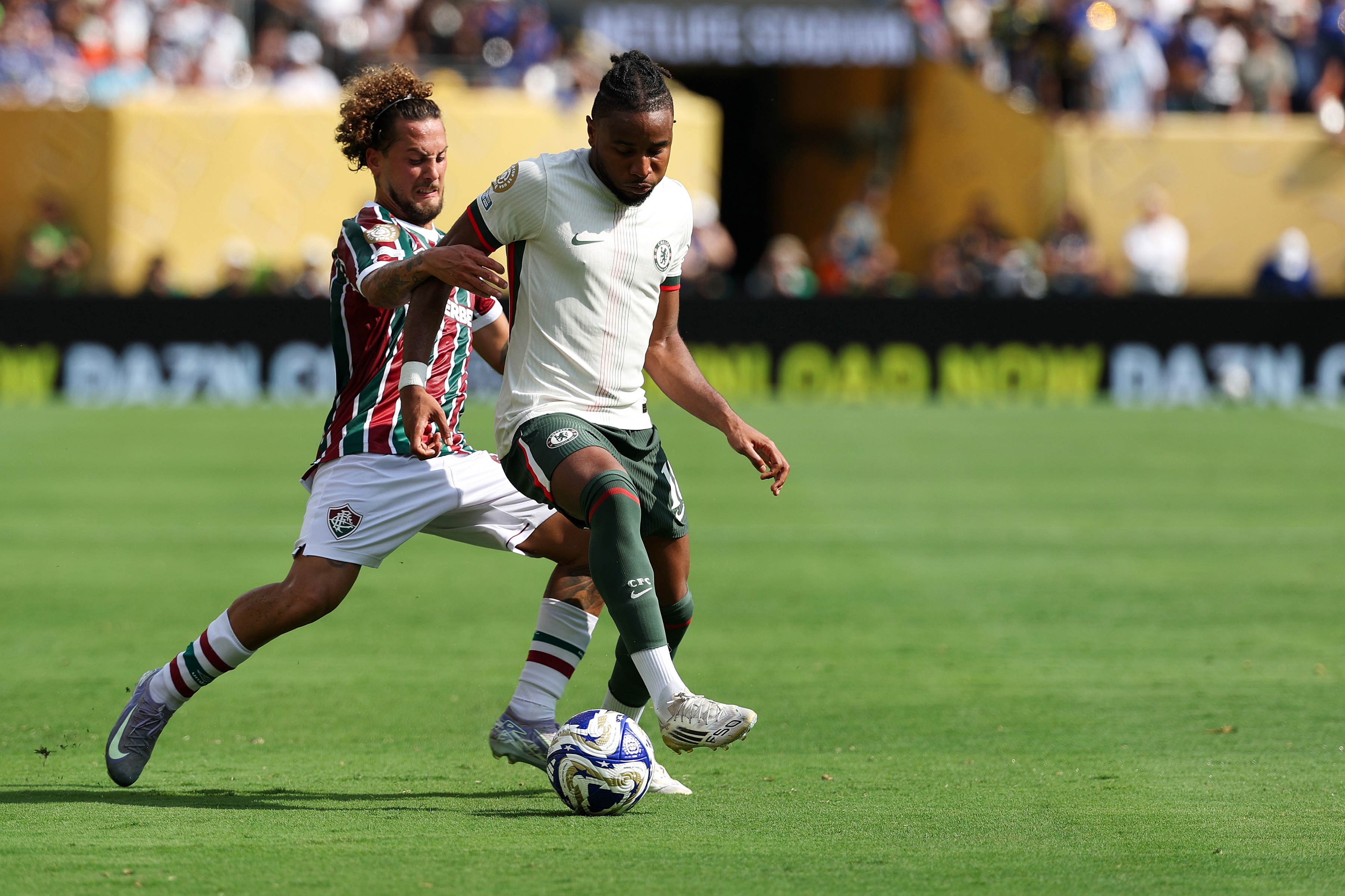 Christopher Nkunku grapples with Fluminense star Guga whilst dribbling with the ball.