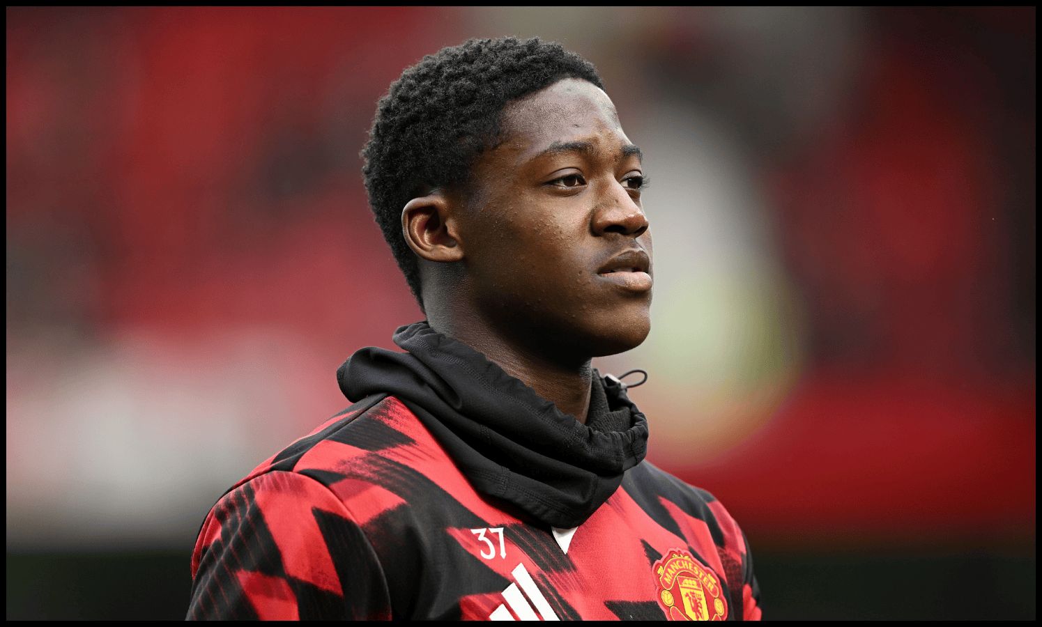 Kobbie Mainoo looks on while warming up for Man United.