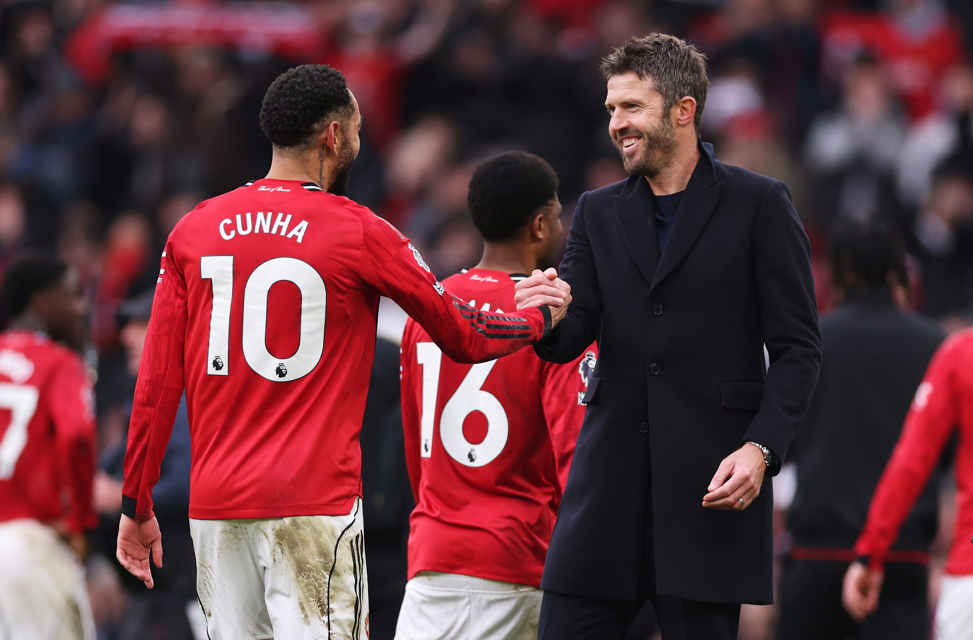 Michael Carrick embraces Matheus Cunha after Man United win the Manchester derby.