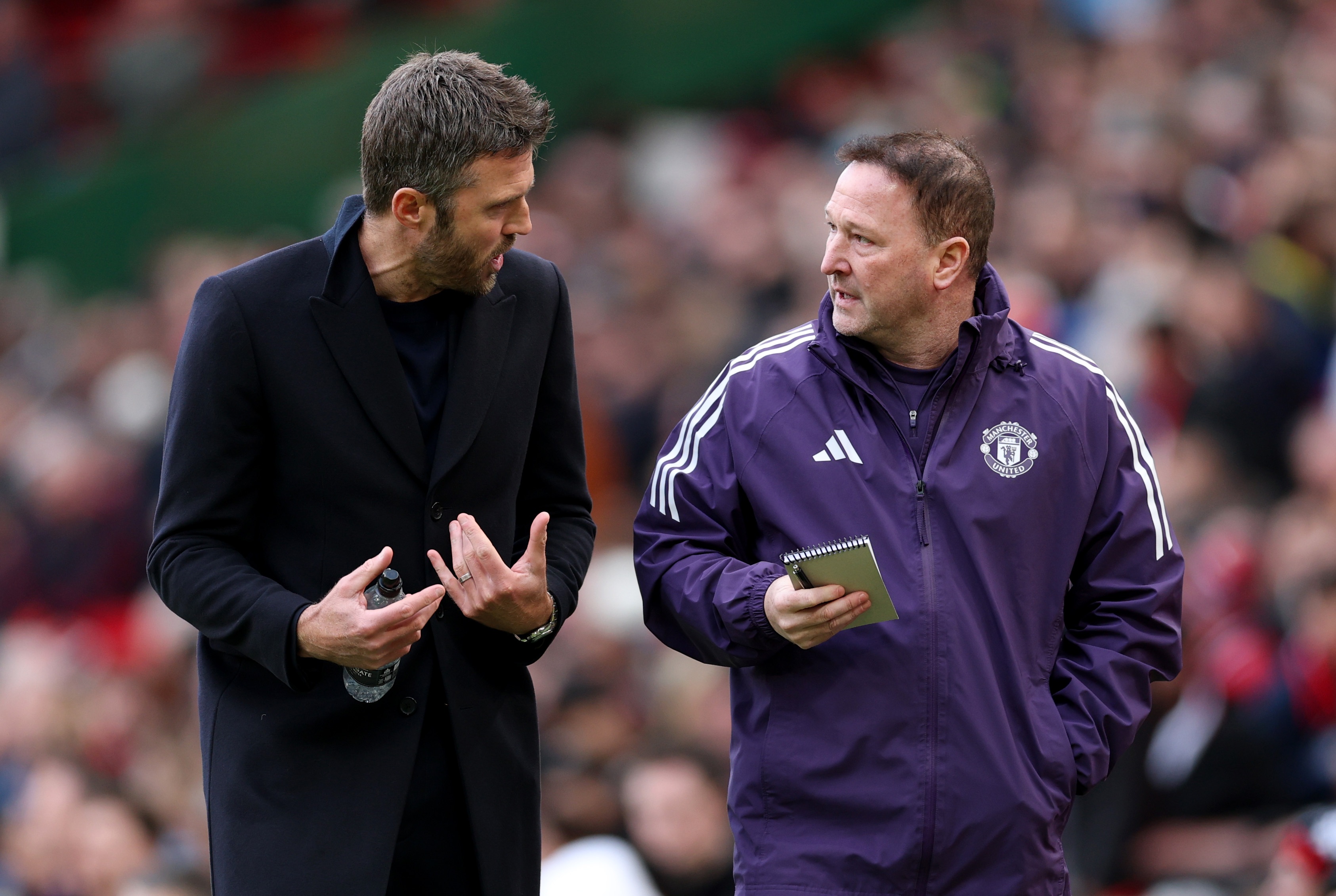 Michael Carrick talks with Steve Holland during Manchester United game.