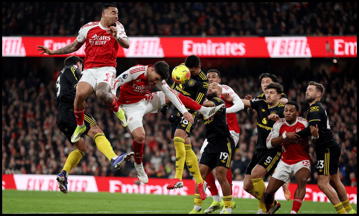 Man United and Arsenal players vie for the ball.