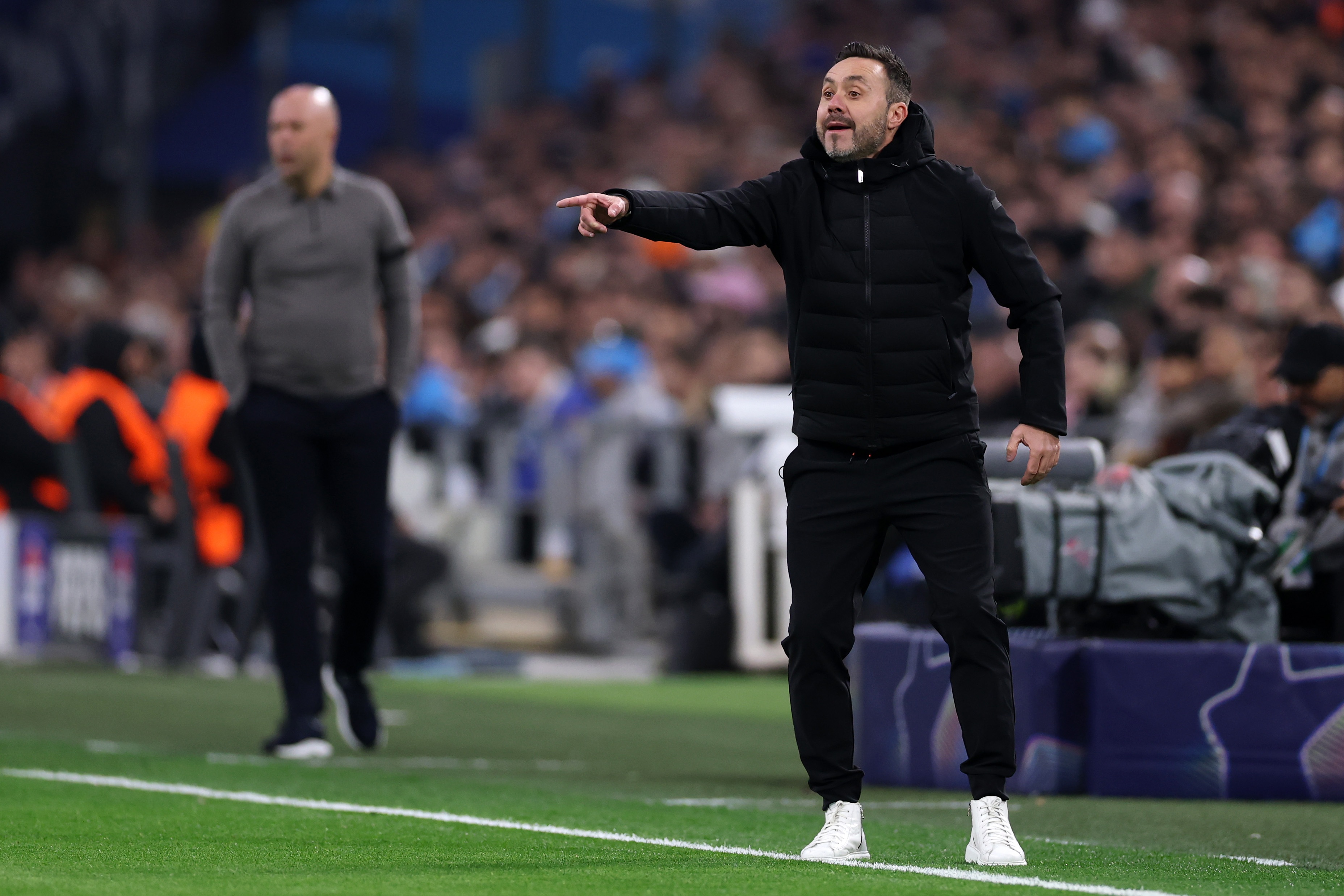 Roberto De Zerbi points at the pitch with an animated face.